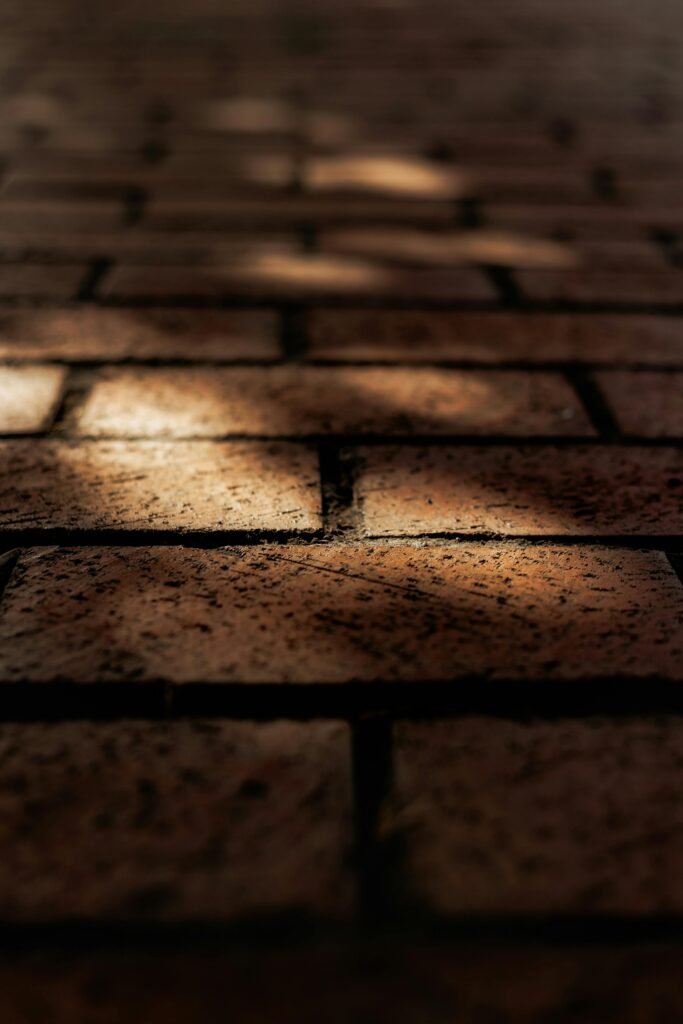 Close-up of red brick pavement with shadows creating a moody atmosphere.
